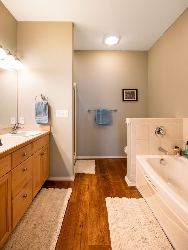 bathroom with hardwood / wood-style floors, vanity, toilet, and a bathing tub