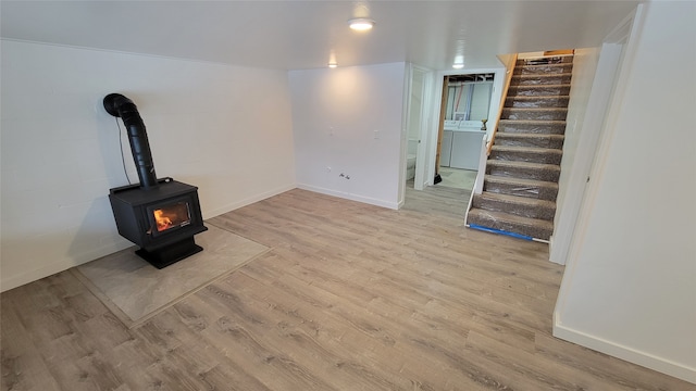 unfurnished living room featuring light wood-type flooring, washer / clothes dryer, and a wood stove