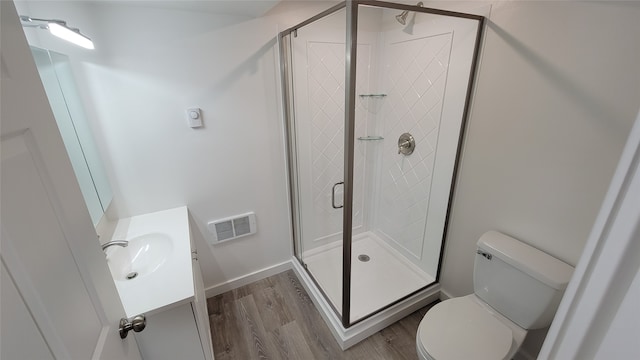 bathroom with hardwood / wood-style floors, vanity, toilet, and a shower with door