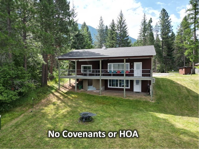 back of property with a lawn and a deck with mountain view