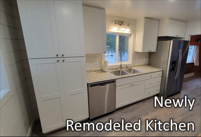 kitchen with light hardwood / wood-style floors, white cabinetry, sink, and appliances with stainless steel finishes