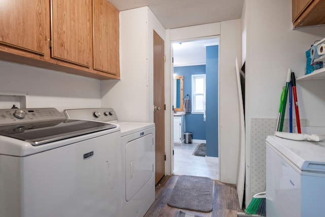 laundry room with washer and clothes dryer, cabinets, a textured ceiling, and hardwood / wood-style flooring