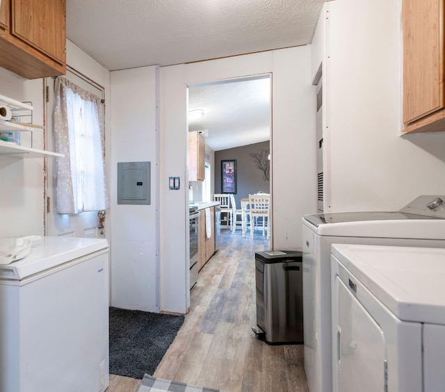 laundry area with cabinets, a textured ceiling, light hardwood / wood-style flooring, washing machine and clothes dryer, and electric panel