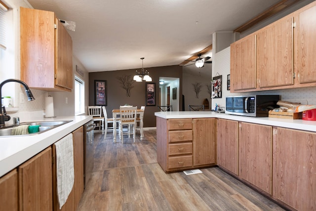 kitchen with appliances with stainless steel finishes, vaulted ceiling, dark wood-type flooring, sink, and pendant lighting