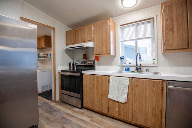 kitchen featuring sink, vaulted ceiling, a textured ceiling, light hardwood / wood-style floors, and stainless steel appliances