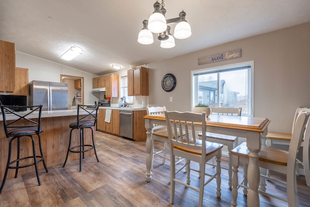 dining space featuring sink, vaulted ceiling, hardwood / wood-style flooring, a textured ceiling, and a notable chandelier