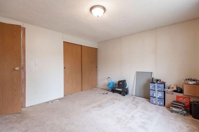 carpeted bedroom with a textured ceiling and a closet