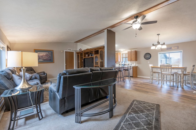 living room featuring a textured ceiling, vaulted ceiling with beams, wood-type flooring, and ceiling fan with notable chandelier