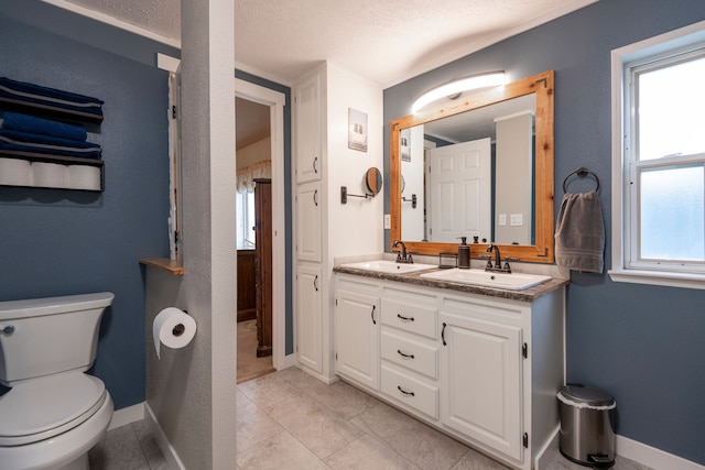 bathroom featuring tile patterned flooring, vanity, toilet, and a textured ceiling