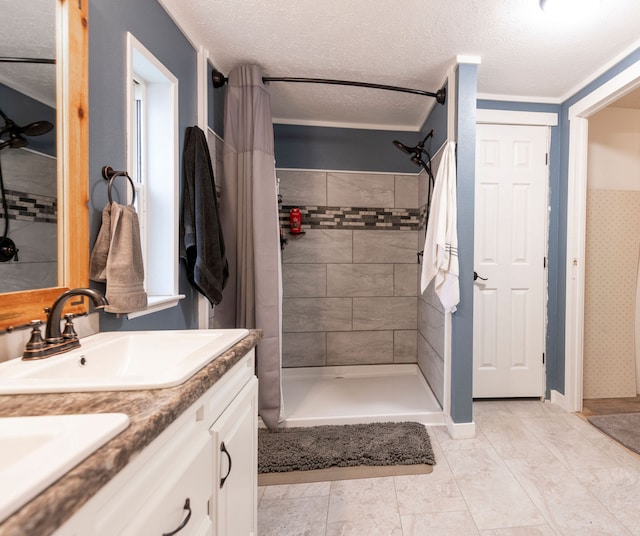 bathroom with vanity, a tile shower, ornamental molding, and a textured ceiling