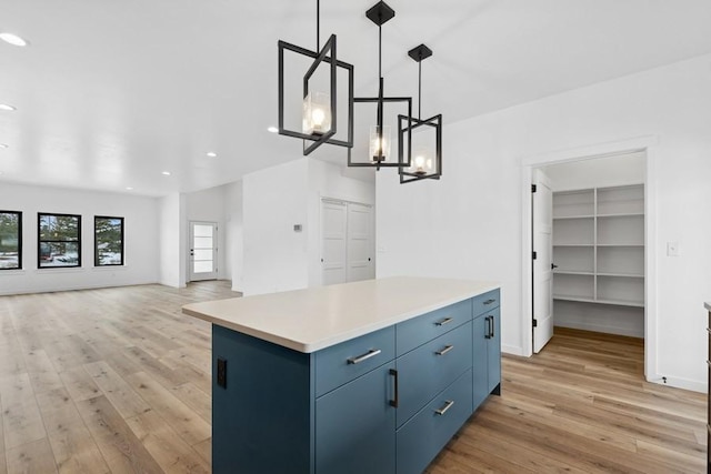 kitchen featuring pendant lighting, light wood-type flooring, a kitchen island, and blue cabinets