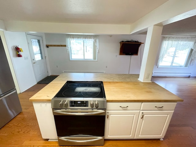 kitchen featuring butcher block countertops, plenty of natural light, white cabinets, and stainless steel appliances