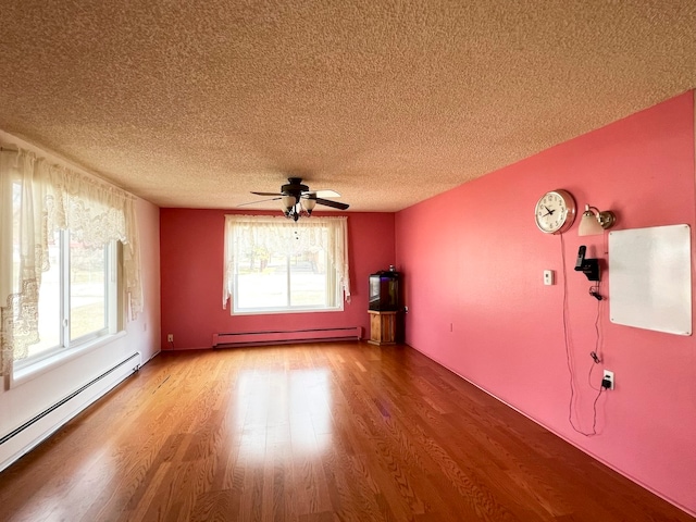 empty room with ceiling fan, light hardwood / wood-style floors, a textured ceiling, and a baseboard heating unit