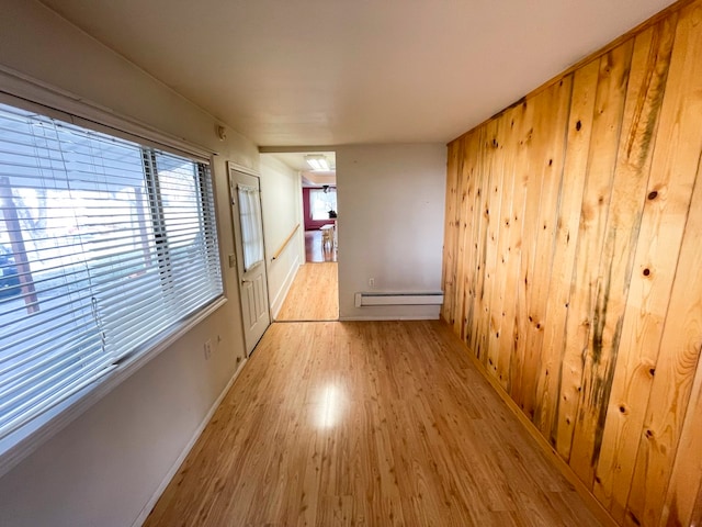 corridor featuring baseboard heating, wood walls, and light wood-type flooring