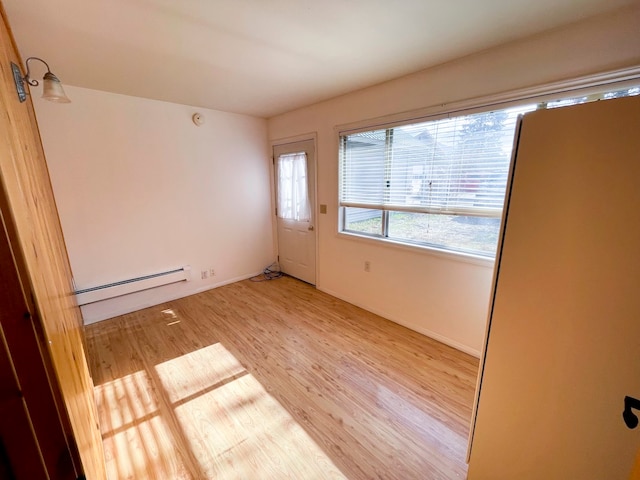 unfurnished room featuring baseboard heating and light hardwood / wood-style floors