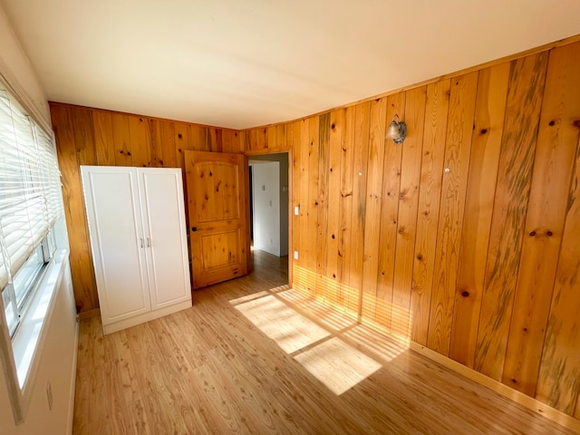 unfurnished bedroom with light wood-type flooring and wood walls