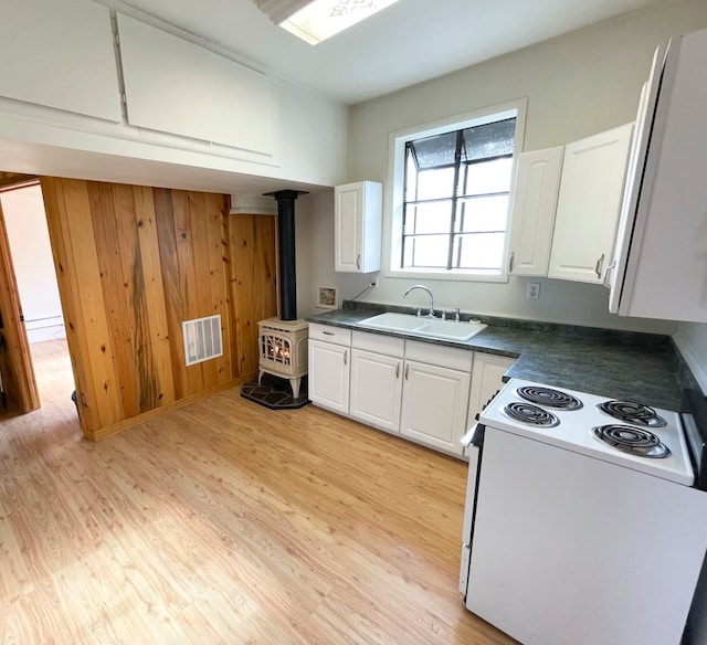 kitchen featuring white cabinets, electric stove, a wood stove, and sink