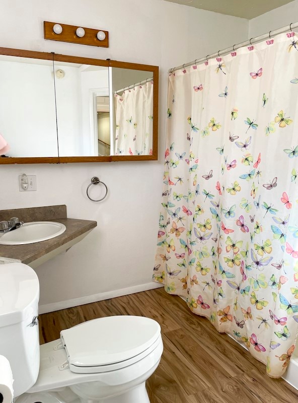 bathroom featuring hardwood / wood-style flooring, toilet, sink, and a shower with shower curtain