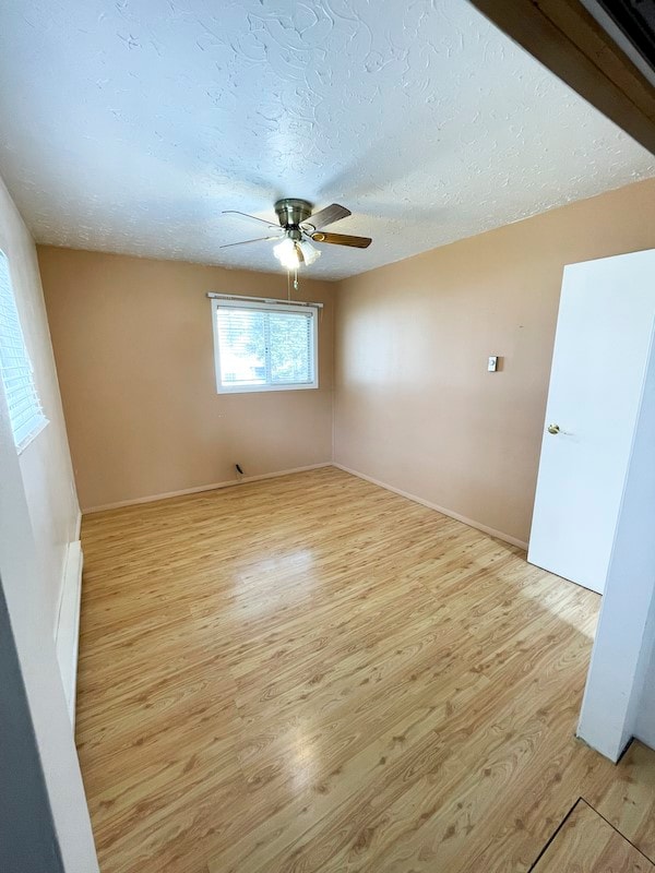 spare room with ceiling fan, light wood-type flooring, and a textured ceiling