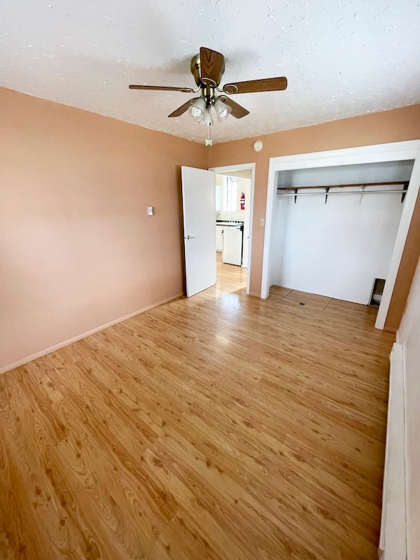 unfurnished bedroom with light wood-type flooring, a closet, and ceiling fan