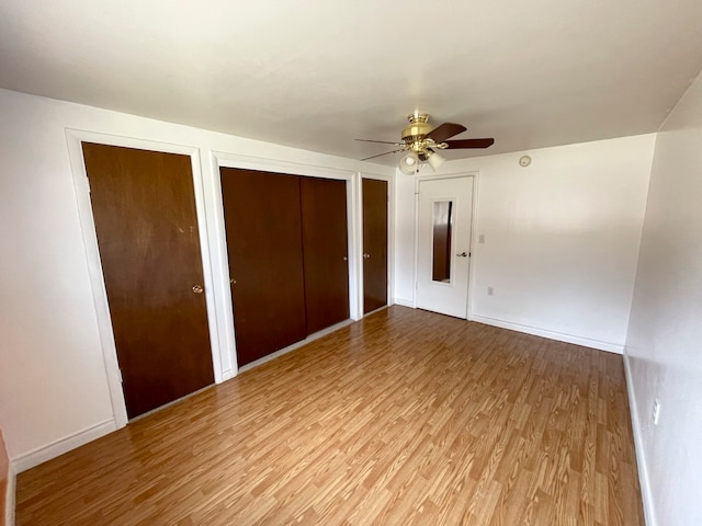 unfurnished bedroom featuring two closets, light hardwood / wood-style flooring, and ceiling fan