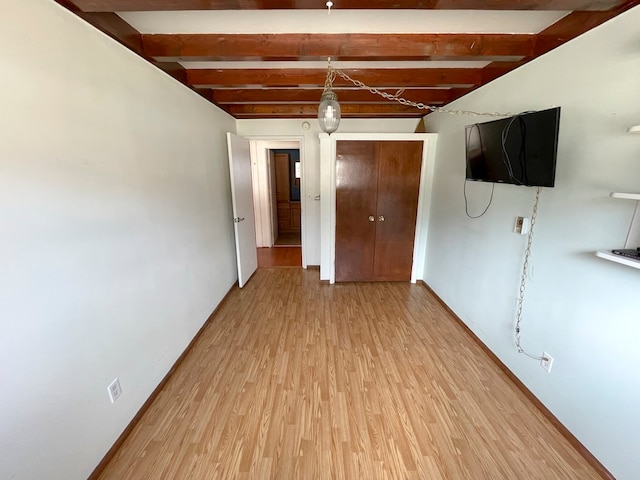 empty room featuring beam ceiling and light hardwood / wood-style flooring