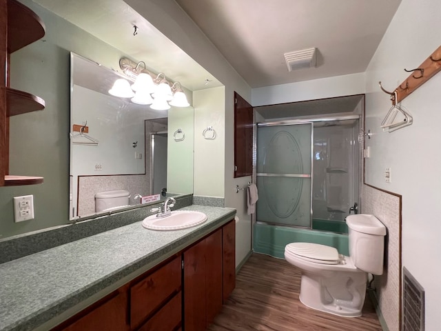 full bathroom with wood-type flooring, vanity, toilet, and enclosed tub / shower combo