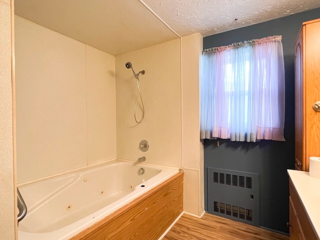 bathroom featuring vanity, hardwood / wood-style flooring, a textured ceiling, radiator heating unit, and tub / shower combination