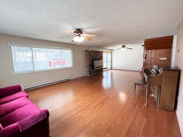 living room featuring light wood-type flooring, a wealth of natural light, and a baseboard radiator