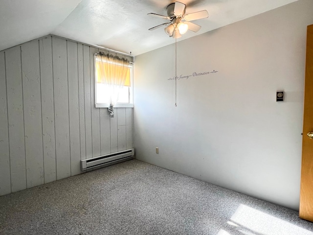 empty room with carpet flooring, ceiling fan, wooden walls, a baseboard heating unit, and lofted ceiling