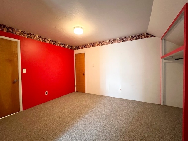 spare room with carpet flooring and vaulted ceiling