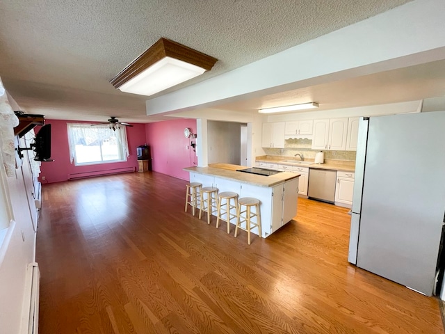 kitchen featuring a breakfast bar, a center island, light hardwood / wood-style floors, white cabinetry, and stainless steel appliances