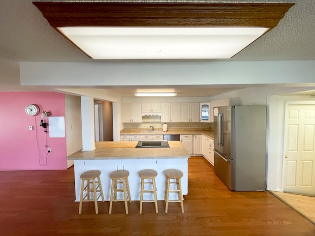 kitchen featuring a kitchen breakfast bar, sink, hardwood / wood-style flooring, white cabinetry, and stainless steel appliances