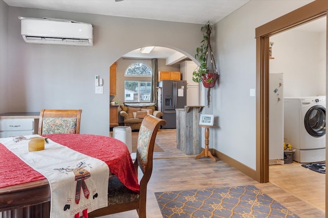 dining area with washer / clothes dryer, light hardwood / wood-style flooring, and a wall mounted AC