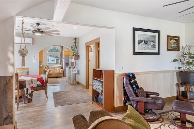 living area with light hardwood / wood-style floors, beam ceiling, a wall mounted AC, and coffered ceiling