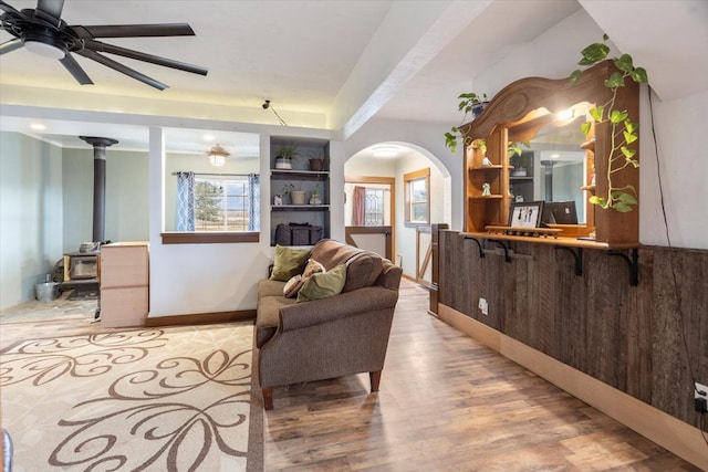 living room featuring light hardwood / wood-style flooring, a wood stove, and ceiling fan