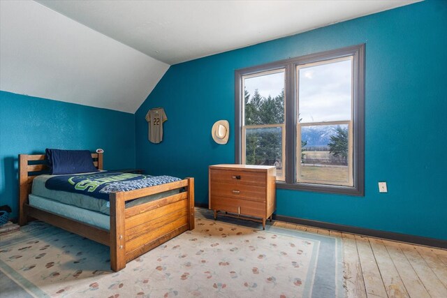 bedroom featuring lofted ceiling and light hardwood / wood-style flooring