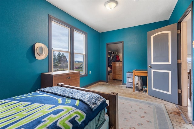 bedroom with a closet, a walk in closet, and light hardwood / wood-style flooring