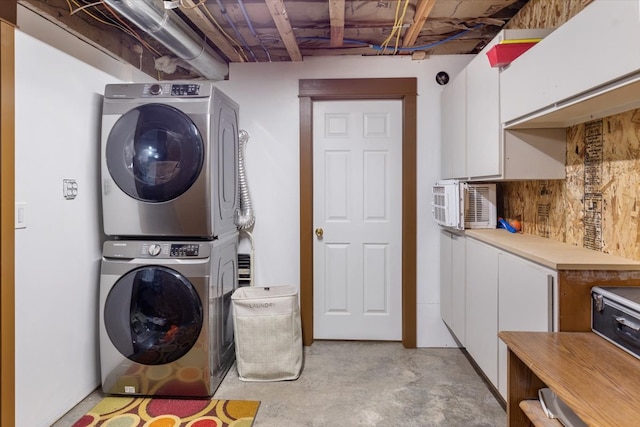 clothes washing area with cabinets and stacked washer / dryer