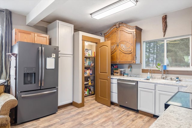 kitchen featuring white cabinets, sink, light hardwood / wood-style flooring, appliances with stainless steel finishes, and beamed ceiling