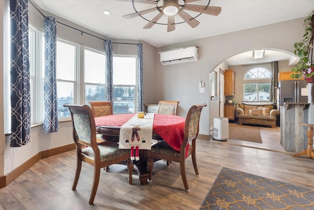 dining area featuring a wall mounted air conditioner, light hardwood / wood-style flooring, and ceiling fan