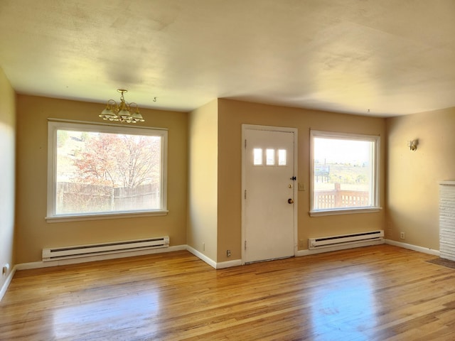 entrance foyer with light hardwood / wood-style floors, an inviting chandelier, and a baseboard heating unit