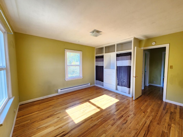 unfurnished bedroom with a closet, light hardwood / wood-style flooring, and a baseboard radiator