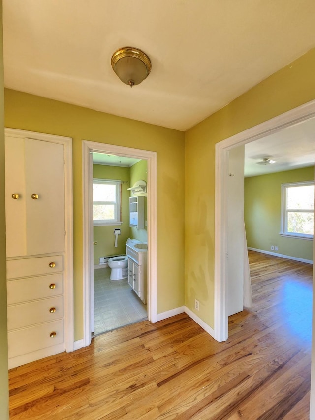 hall with a wealth of natural light and light hardwood / wood-style flooring