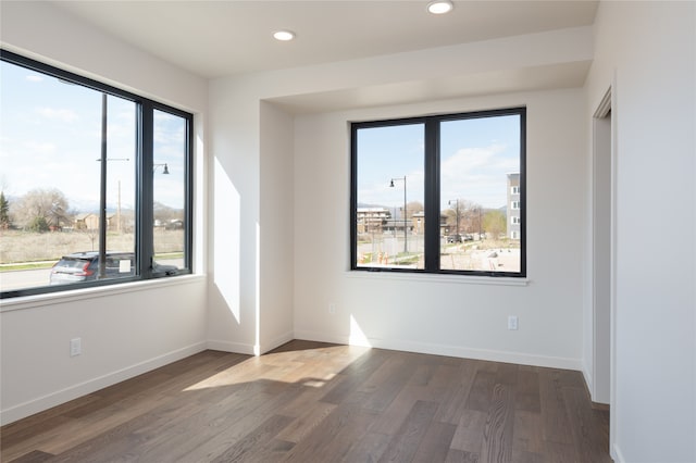 empty room with dark hardwood / wood-style flooring and plenty of natural light