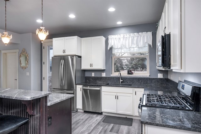 126 Moes Run, Kalispell, MT 59901 - kitchen with a sink, appliances with stainless steel finishes, white cabinets, and dark stone countertops
