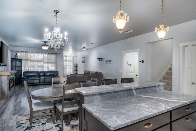 126 Moes Run, Kalispell, MT 59901 - kitchen with a center island, light stone countertops, ceiling fan with notable chandelier, and decorative light fixtures
