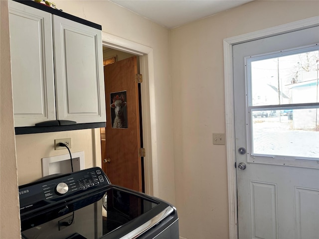 clothes washing area with washer / clothes dryer and cabinets