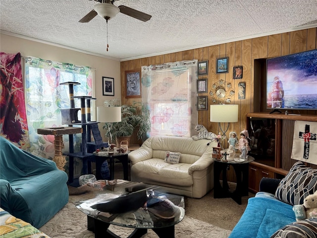 carpeted living room featuring ceiling fan, wood walls, and crown molding