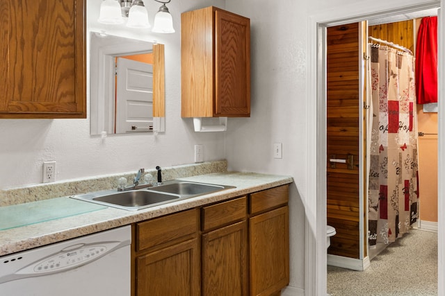 kitchen featuring pendant lighting, dishwasher, sink, and light carpet